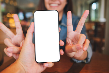 Mockup image of a man holding mobile phone with blank screen with a cheerful woman in background