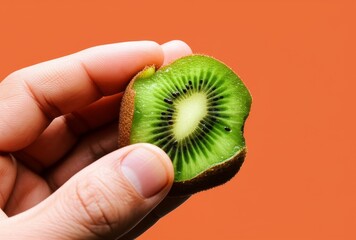 A half kiwi fruit held by a human hand