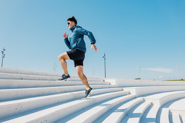 Dynamic Athletic Man Ascending Modern Outdoor Steps Under a Clear Blue Sky During a Bright and...