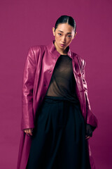 Fashion asian woman in purple leather jacket and black pants posing against a purple background