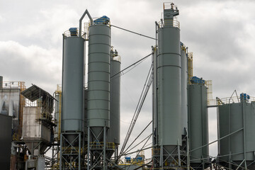 Industrial silos storing cement in a cloudy sky: cement production infrastructure