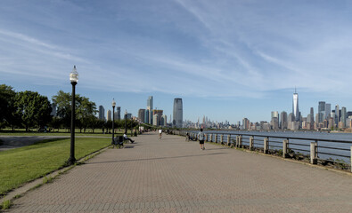 View of pedestrian walkway in Liberty State Park, Jersey City, NJ with view of downtown Manhattan New York City skyline.