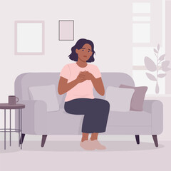 A woman is sitting on a couch, feeling chest pain and discomfort.