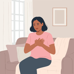 A woman sitting on a sofa with her hands on her chest, feeling unwell.