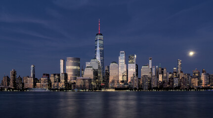 Fototapeta premium new york city downtown manhattan skyline at sunset blue hour long exposure skyscraper buildings reflecting sunlight with moon rising in background nyc travel tourism usa photo photography