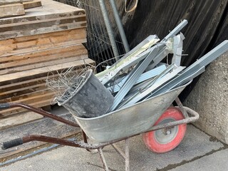 A construction site with a stack of wooden panels in front of a construction fence. In the...