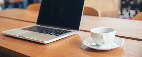 Home Office Desk Concept.Laptop and cup of coffee placed on wooden desk-computer for planner to plan job, working space at home-banner image.