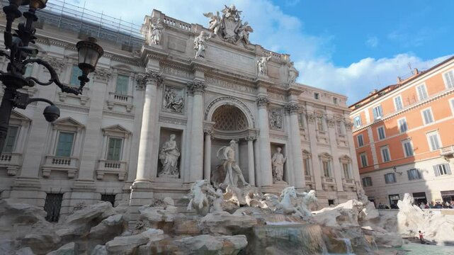 The trevi fountain, a baroque masterpiece in rome, stands tall against a clear blue sky, its sculpted figures and cascading water captivating tourists