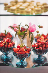 Perfectly arranged fruit bowls with fresh strawberries and elegant peonies on a glass table at a summer gathering in a cozy setting