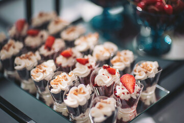 Delicious dessert cups adorned with whipped cream and strawberries tempt guests at a celebration in...