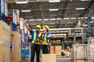 Discussion about machinery layout and traffic paths guided by digital tablet in busy warehouse.