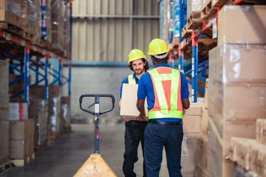Two hardworking employees navigate a storage zone while lifting boxes to the right section. Warehouse and logistic industry worker.