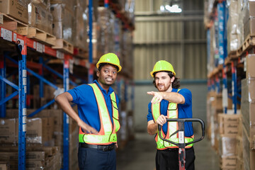 In a busy warehouse, two men push a cart while one gives instructions, pointing out the correct...