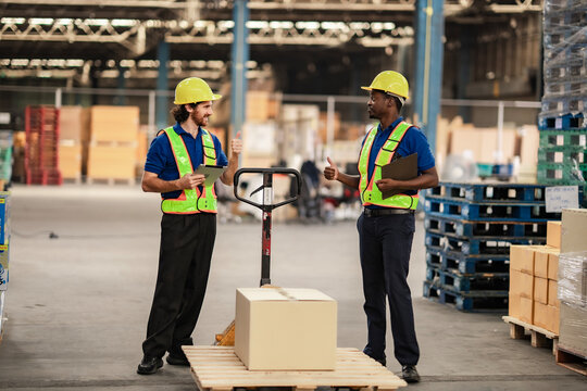 Operational staff push products to the dispatch area while handling work instructions. Worker in warehouse and delivery industry.