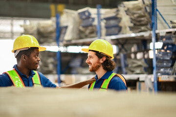 Two male staff members share a light moment during a break, dressed in industrial uniforms and hard hats.