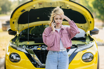 A young woman stands by her car, feeling confused and anxious, and calls for help on the phone. The...