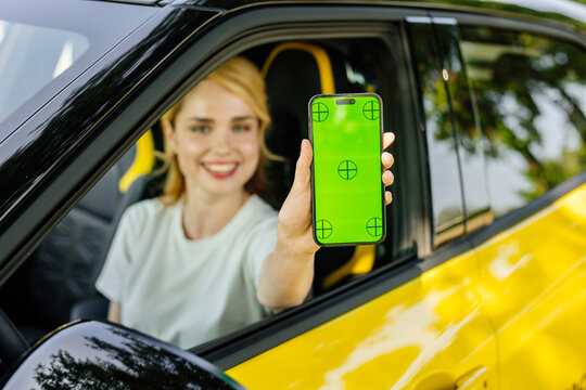 Car rental app. Happy woman showing empty smartphone sitting in car, smiling woman showing a place to copy a mobile ad or website.