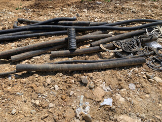 Old dirty hoses scattered on ground at construction site, gritty industrial scene, suitable for themes of urban decay, construction, and infrastructure