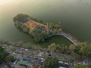 Views of West Lake in Hanoi with the iconic temple surrounded by lush greenery and tranquil waters at sunset