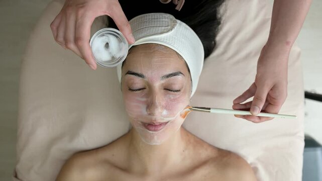 Beautician applying a hydrafacial mask to a client, slow motion overhead shot, close up