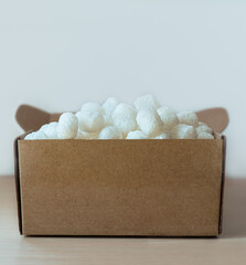 close-up of cardboard box filled with eco-friendly corn based packing peanuts Sustainable packaging for safe and conscious shipping, logistics and online shopping themes