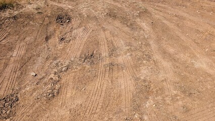 Tire tracks intersecting on parched ground, forming intricate patterns against bright sunlight, revealing weathered desert landscape's textural complexity