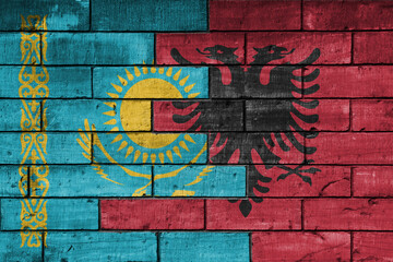 colourful painted big national flag of albania and flag of kazakhstan on a massive old brick wall background. concept