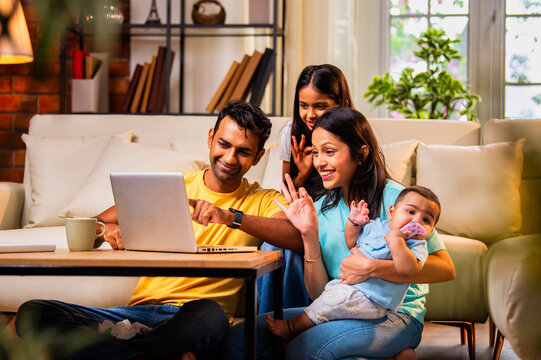 Young family using laptop indoors on sofa for shopping, surfing, and spending time together happily