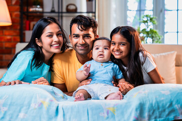 Smiling Indian family sitting on floor near sofa, bonding together in stylish cozy living room