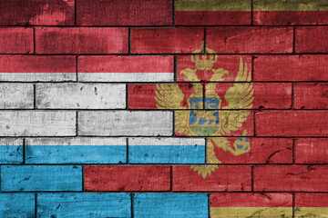 Fototapeta premium colourful painted big national flag of montenegro and flag of luxembourg on a massive old brick wall background. concept