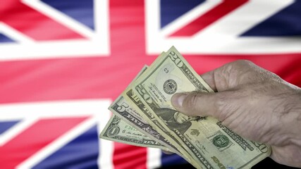 Hand holding a group of american banknotes with a british flag on background, representing free trade agreement between UK and USA. - Powered by Adobe