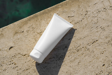 White mockup cosmetic cream tube placed on a textured stone surface, illuminated by natural light....