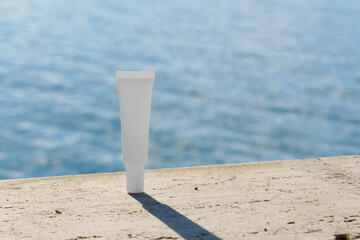White cosmetic tube mockup set on stones by the ocean. Clean background perfect for natural...