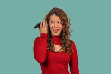 Young woman listening to voice message on smartphone with curious expression