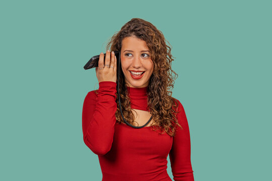 Young woman listening to voice message on smartphone with curious expression