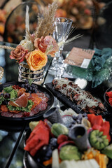  Elegant table setting featuring a charcuterie spread with prosciutto, salami, and fresh fruits, complemented by vibrant floral arrangements in autumn hues, creating a luxurious atmosphere.