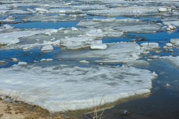 Massive ice floes slowly move along the Bakhthiyar River as the ice breaks up during the spring thaw in a quiet, remote region.