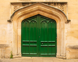 antique green door of building (church, cathedral) with decorative moulding on wall in oxford