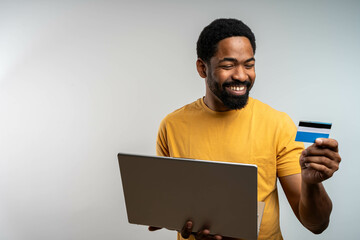 Happy cheerful smiling young adult man doing online shopping or e-shopping satisfied entrepreneur...