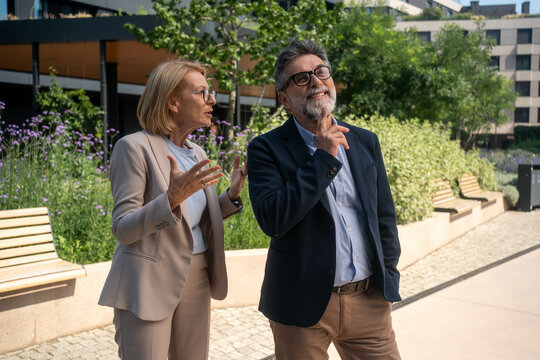 Angry businesswoman arguing with indifferent businessman outdoors in modern business district