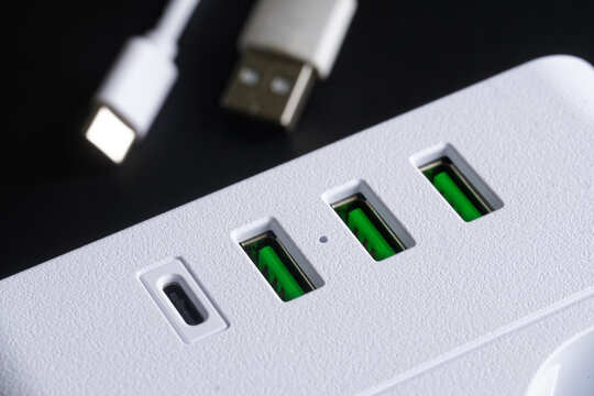 Close-up of a modern white USB charging station with multiple Type-A and Type-C ports alongside USB plugs. Ideal for tech reviews, product showcases, and digital workspace setups