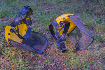 two yellow and black protective face shields resting on green grass, concept of safety equipment,...