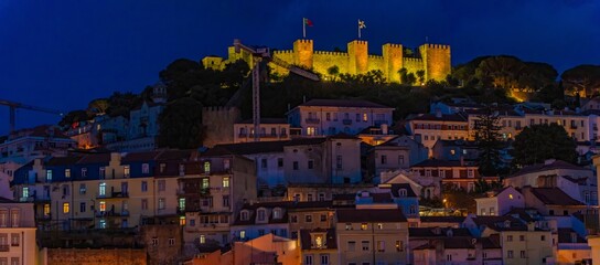 Night view of the illuminated S. Jorge Castle on a hill in the Alfama district of Lisbon.