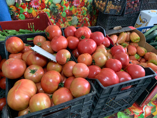 Ripe pink and red tomatoes in crates at market, fresh vegetables on stall