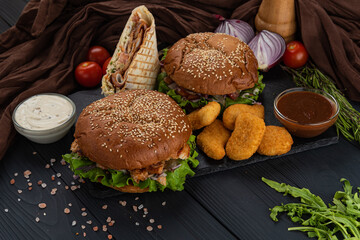 Burgers, naggets, and shawerma on black background with sauce