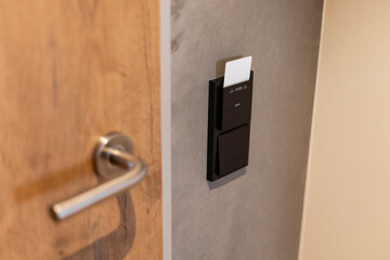 A sleek card reader is installed on a gray wall next to a wooden door. This device allows access using a keycard in a contemporary environment, enhancing security and convenience