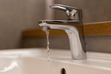 Modern faucet releases a steady stream of water into a clean white sink, showcasing elegant design in a stylish bathroom environment, with a soothing aesthetic