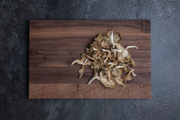 Top-down view of wooden board with pile of dried mushrooms  
