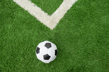 Soccer Ball on Green Grass Field with White Corner. Football stadium background. View from above.