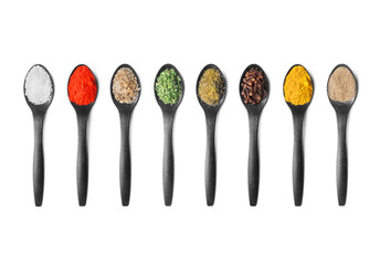 A row of black spoons filled with various colorful spices and seasonings, neatly arranged on a white background